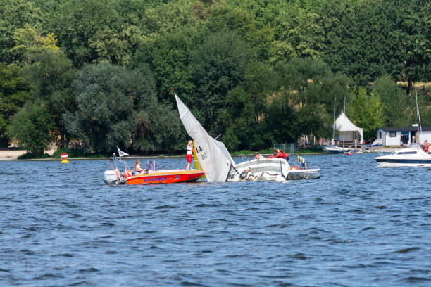 capsized sailboat Berlin, Berlin/Germany - 07.23.2018: A sailboat, which is capsized and raised again with the help of the water guard. mast sailing photos stock pictures, royalty-free photos & images