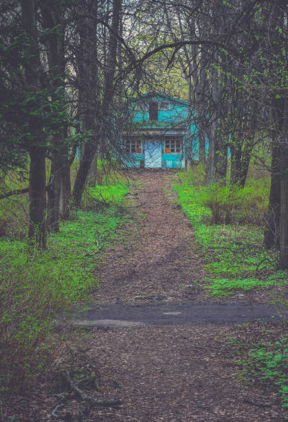 abandoned dilapidated house on a dark wooded bank is ready to collapse into the river