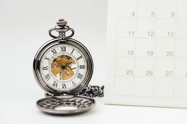 Photo of Vintage pocket watch with white clean desktop calendar on white background using as time passing, time management, year change or deadline concept