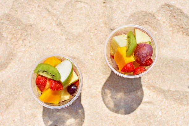 ビーチでのプラスチックカップでおいしいフルーツサラダ - fruit cup ストックフォトと画像