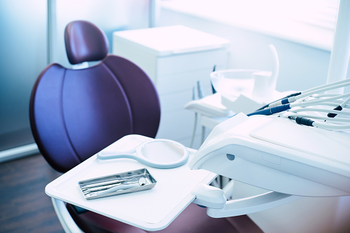 Observando un gabinete. Una sala llena de suplemento médico que consiste en silla dental, luz, espejo, explorador y un pulidor de dientes. photo