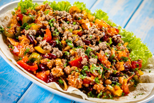 Pork meat, nachos and vegetables on wooden background