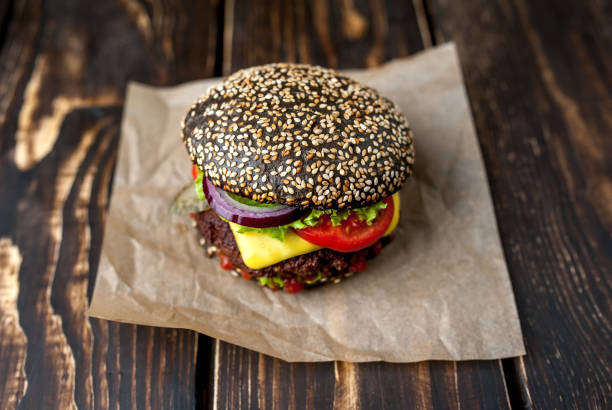 istock Beef hamburger with black bun with lettuce and ketchup served on a rustic wooden table 1137972456