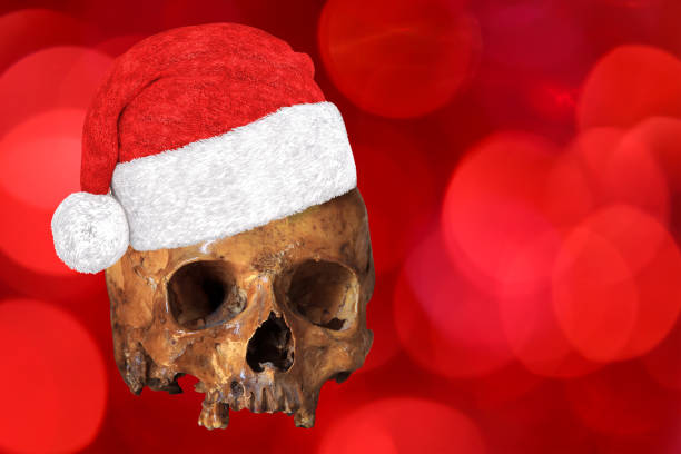 istock Human skull wearing xmas or christmas hat on red bokeh background. It can be used for Boring holiday or old celebration or funny bizarre wishes concept 1137972740
