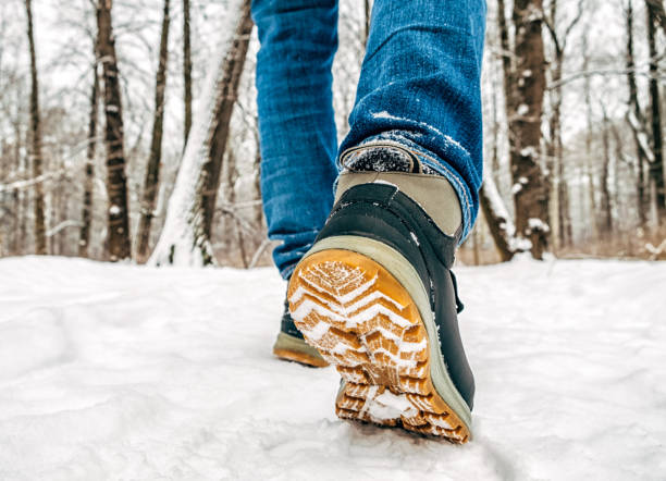 istock Man's legs in black with orange boots walking in the snow 1137973913