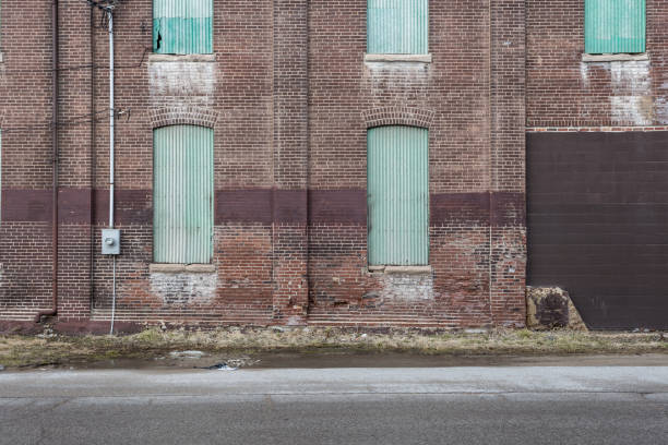 istock Side wall with boarded up windows and doors of an abandoned red brick factory 1137980033