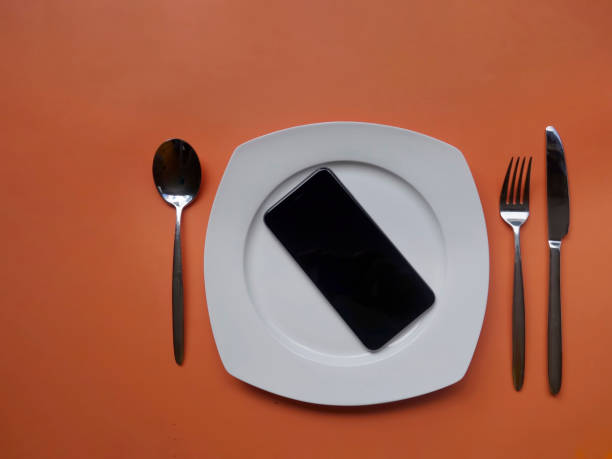 istock cutlery and tablet phone on white plate on oranj background 1137980507