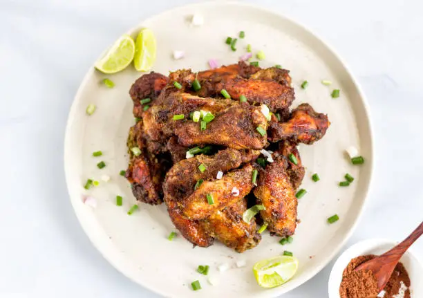 Caribbean / Jamaicxan Style Jerk Chicken Wings on a Plate, Top View. Chicken Appetizer, Dry Rub Chicken Wings, Popular Caribbean and American Cuisine.