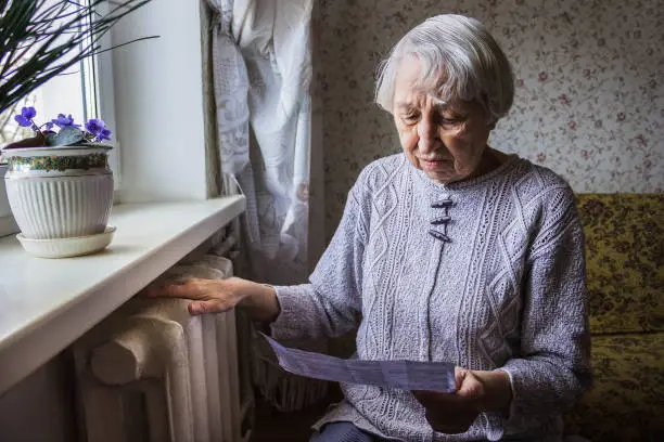 Photo of Woman holding cash in front of heating radiator. Payment for heating in winter. Selective focus.