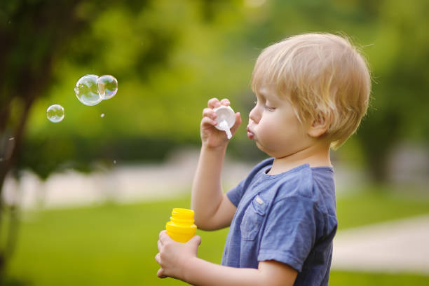 istock Cute little boy blowing soap bubbles in park 1137989040