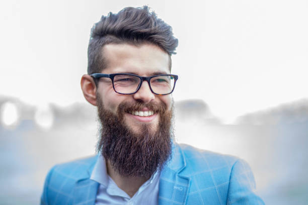Portrait of  young bearded man in  blue dress with a pair of glasses