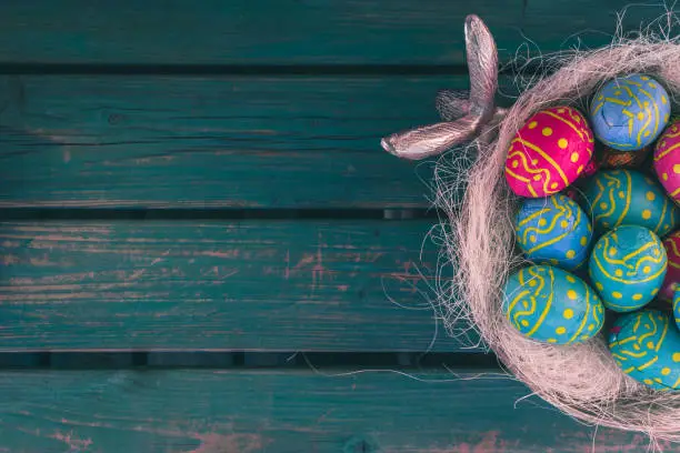 Colored easter eggs in a bowl standing on a green wooden bench, Amsterdam the Netherlands, 23 march 2019