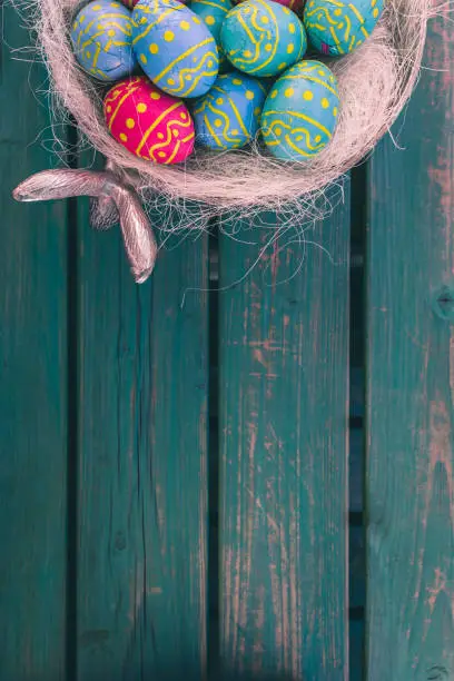 Colored easter eggs in a bowl standing on a green wooden bench, Amsterdam the Netherlands, 23 march 2019