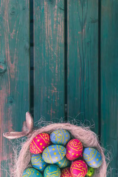 Colored easter eggs in a bowl standing on a green wooden bench, Amsterdam the Netherlands, 23 march 2019