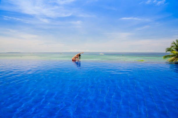 istock Young woman practicing yoga on the Infinity pool 1137991270