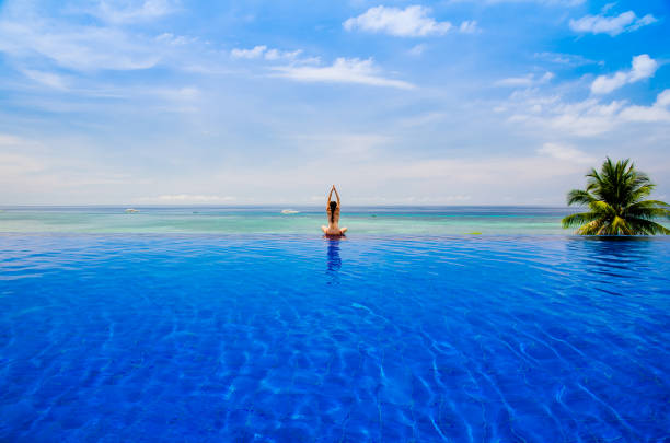 istock Young woman practicing yoga on the Infinity pool 1137991294