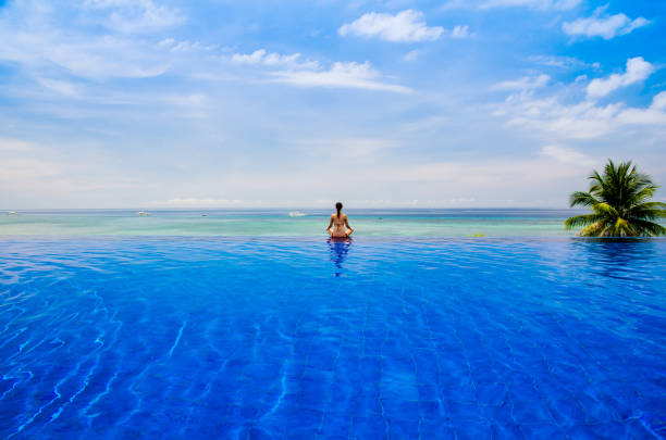 Young woman practicing yoga lotus position on the Infinity pool