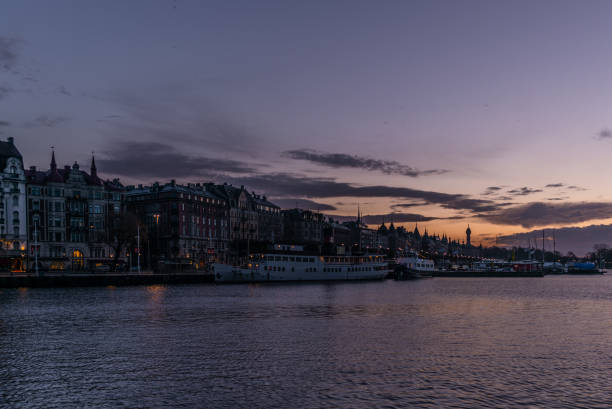 ships in the harbor of  stockholm during a colorful sunrise in winter  with the backdrop of the old town - 1 - stockholm harbor sweden winter imagens e fotografias de stock