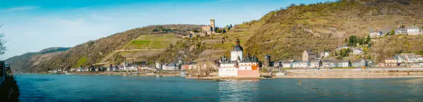 Beautiful view of the historic town of Kaub with famous Burg Pfalzgrafenstein along Rhine river on a scenic sunny day with blue sky in spring, Rheinland-Pfalz, Germany