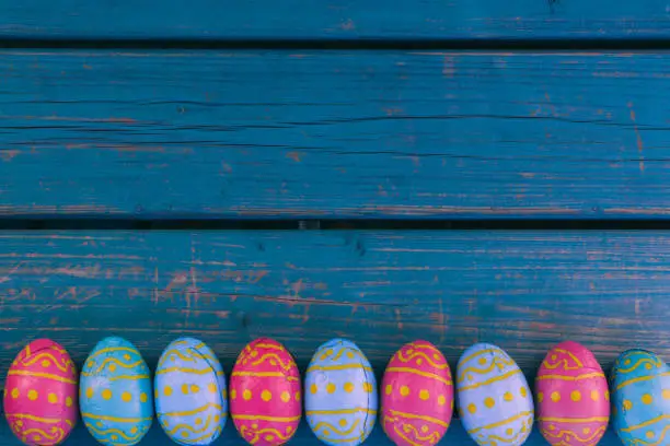 Colored easter eggs in a bowl standing on a blue wooden bench, Amsterdam the Netherlands, 23 march 2019