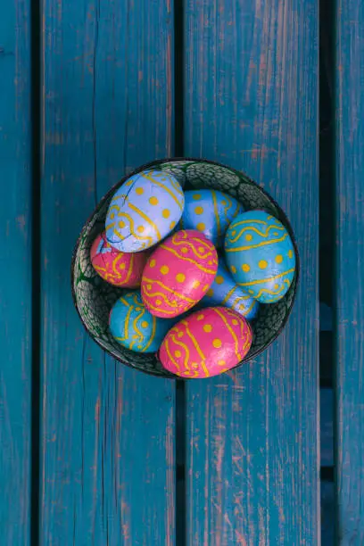 Colored easter eggs in a bowl standing on a blue wooden bench, Amsterdam the Netherlands, 23 march 2019