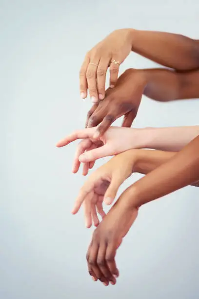 Cropped studio shot of a group of women touching hands against a gray background