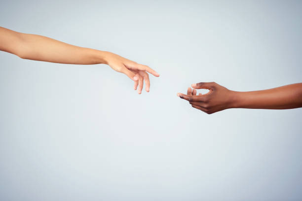 Unity starts with you Cropped studio shot of two women joining their hands against a gray background reaching stock pictures, royalty-free photos & images