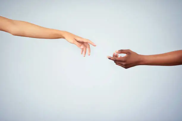Cropped studio shot of two women joining their hands against a gray background