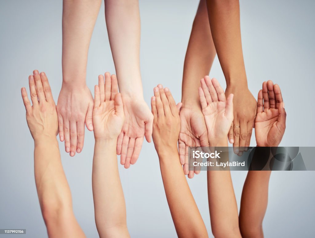 Acceptance is in the hands of all of us Cropped studio shot of a group of women stacking their hands against a gray background Variation Stock Photo