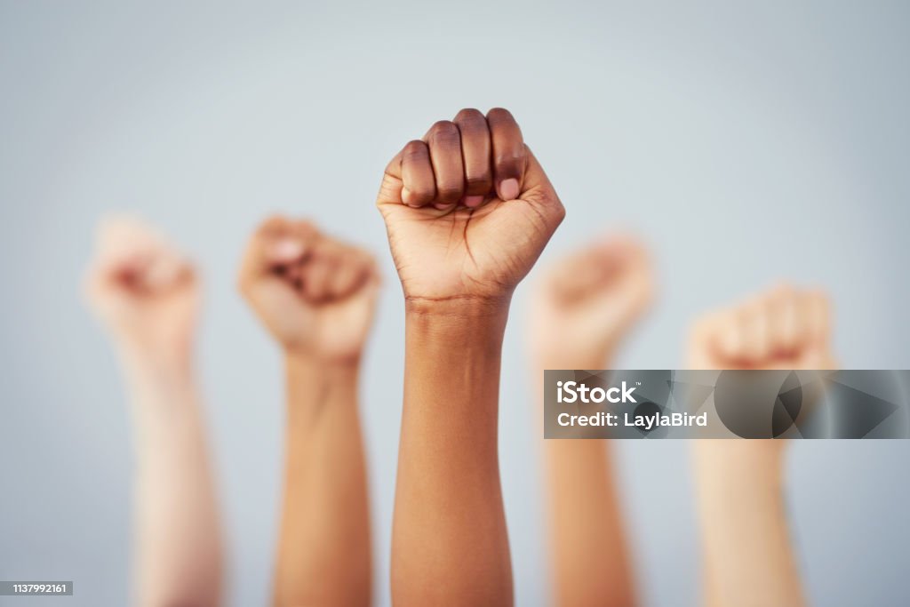 Put the power back in your hands Cropped studio shot of a group of women raising their fists in solidarity against a gray background Women Stock Photo