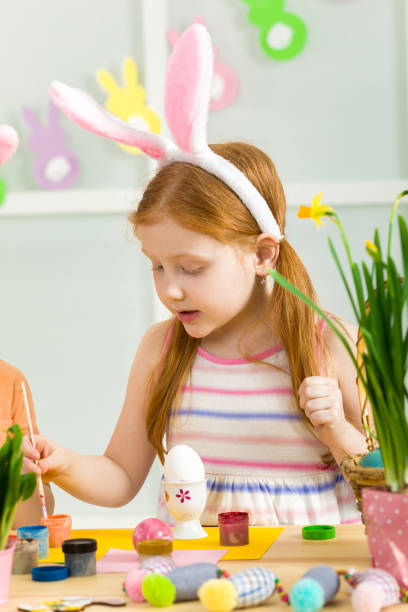 istock little child girl with Easter bunny ears painting Easter eggs 1137994932