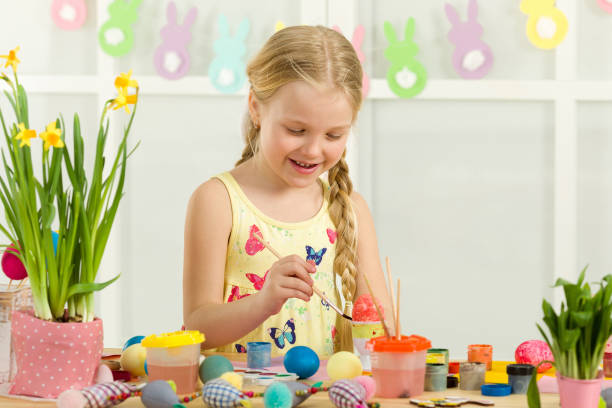 istock little child girl with Easter bunny ears painting Easter eggs 1137995848