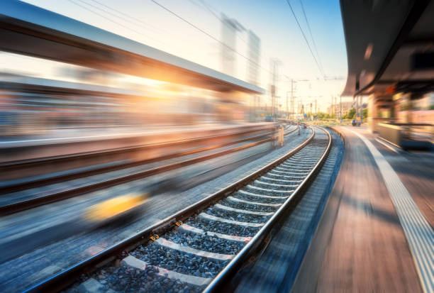 istock Railway station with motion blur effect at sunset. Industrial landscape with railroad, blurred railway platform, sky with orange sunlight in the evening. Railway junction in Europe. Transportation 1137999623
