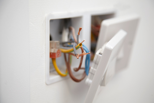 Close up of a 13 amp electrical socket being wired with exposed wires