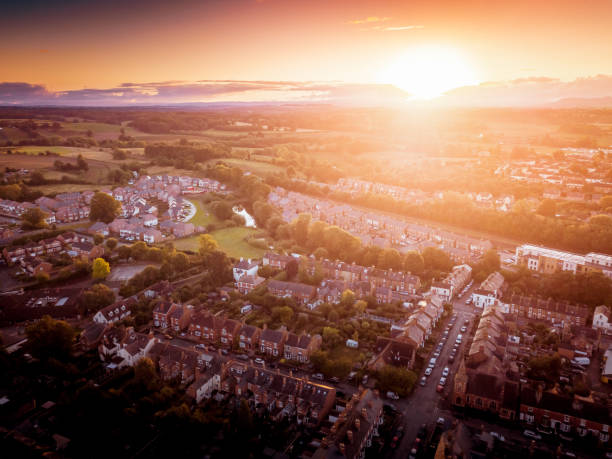 zon setting met atmosferische effect op traditionele britse huizen en met bomen omzoomde straten. - areal stockfoto's en -beelden