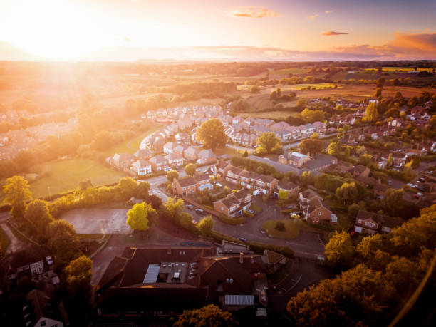 Sun rising above a traditional British housing estate with countryside in the background. Dramatic, warm lighting creates a homely mood. Very typically English houses that are over 100 years old. A picturesque scene, created by the long shadows and warm glow. suburb photos stock pictures, royalty-free photos & images