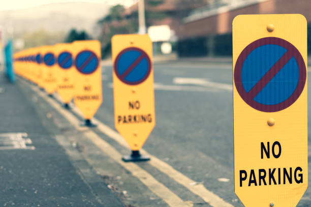'No Parking' road signs and double yellow lines 'No Parking' road signs running along the edge of a city street, which is also marked with and double yellow lines.  Belfast, Northern Ireland. no parking sign photos stock pictures, royalty-free photos & images