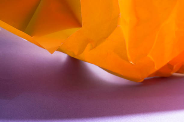 istock Wrinkled Orange papers on purple background 1138013811