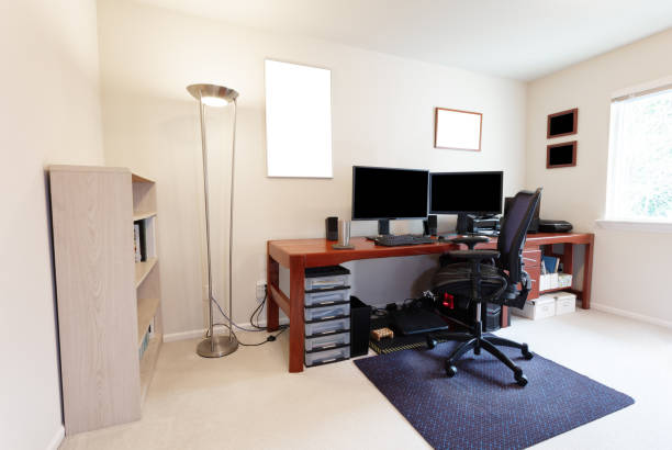 istock Computer chair at large work table with computer monitors and other technology equipment in bright home office interior 1138013910