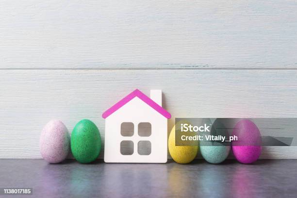 House Model And Painted Easter Eggs Over White Wooden Background Stock Photo - Download Image Now