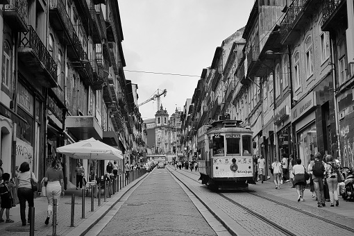 Porto, Portugal - July 30, 2018: Cable car in main street in Porto near Santo Antonio church, the street is full of tourists in a summer afternoon.