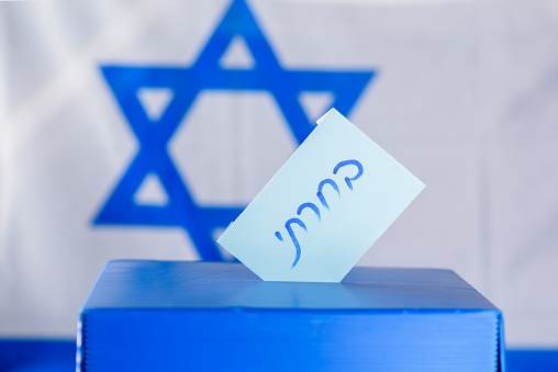 Vote box on election day. Hebrew text I voted on voting paper over Israel flag background. Freedom Democracy Concept.