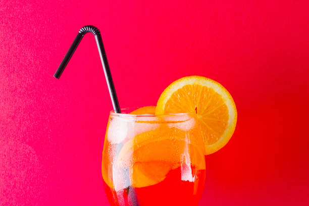 istock Cocktail Spritz on red blue background. Summer alcoholic cocktail with orange slices. Spritz on colored background. Coral colored cocktail in minimalism style 1138022549