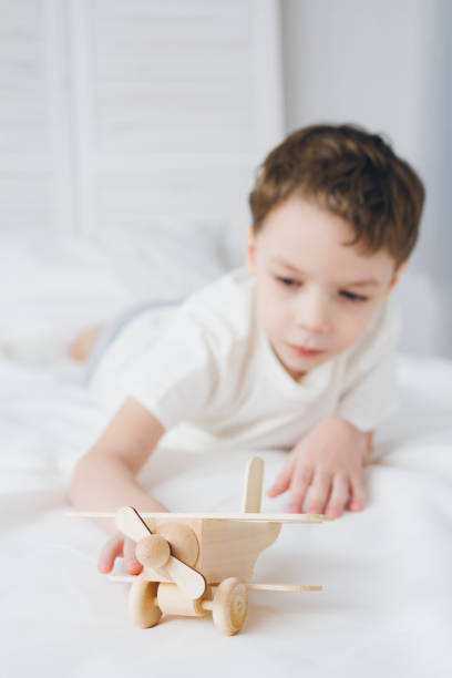 istock Cute boy playing with wooden airplane sitting on the bed 1138022738