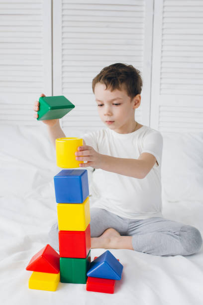 istock Boy plays and builds a tower of colorful plastic cubes 1138022901