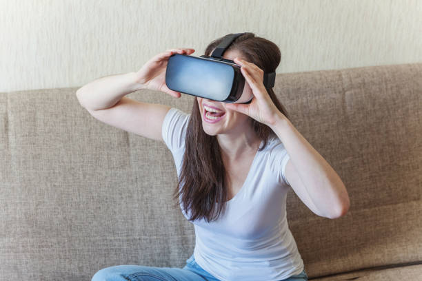 istock Smile young woman wearing using virtual reality VR glasses helmet headset at home 1138029899