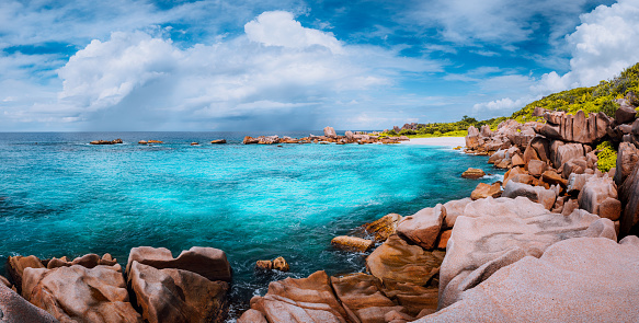 Beautiful panorama with impressive white fluffy clouds wild rocky beach Anse Marron in Seychelles. La Digue.