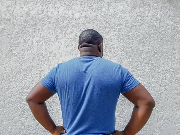 Black and white rear view of man's back. Shaved head.