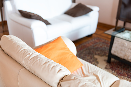 Interior high angle of modern decoration in room with furniture couch white leather sofa and orange pillows with bright natural light