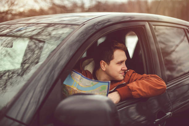 istock Young man with map traveling by car 1138041089